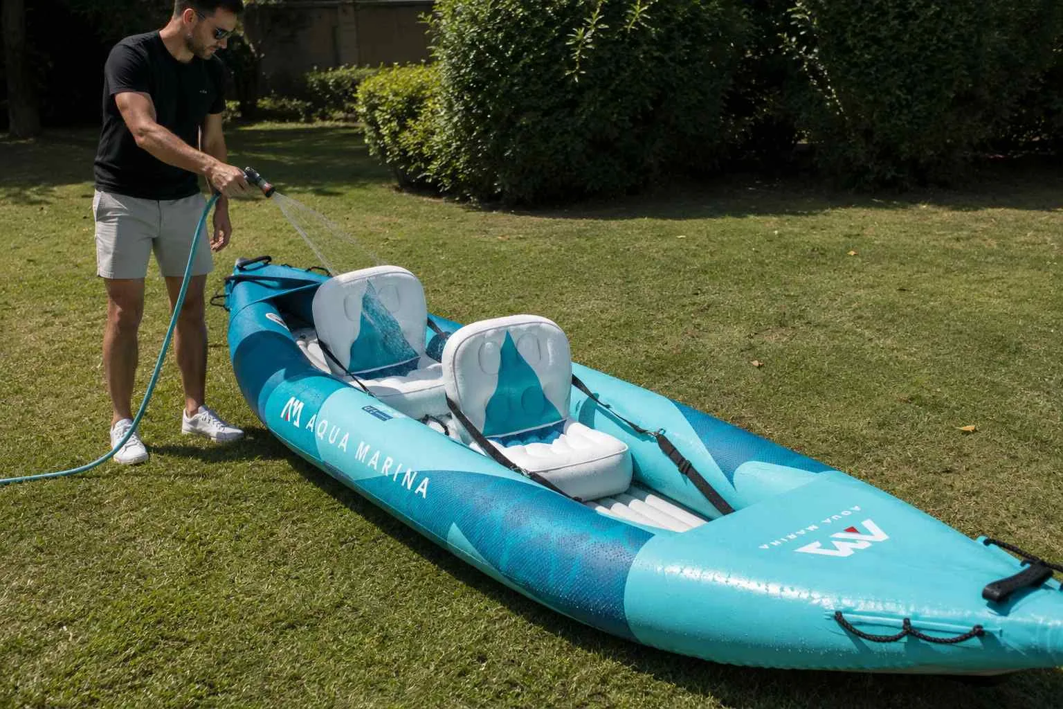 Kayak gonflable rincé au tuyau d'arrosage sur une pelouse